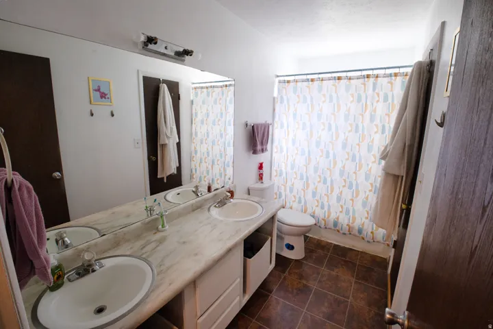 Dual vanity with integral sinks, large wall-mounted mirror, and tile flooring