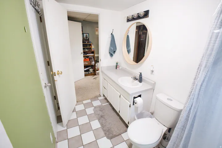 White vanity with an integrated sink, a rounded mirror, and a three-light fixture