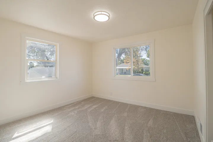 Neutral wall finishes, plush carpet flooring, two windows, and a ceiling-mounted light fixture