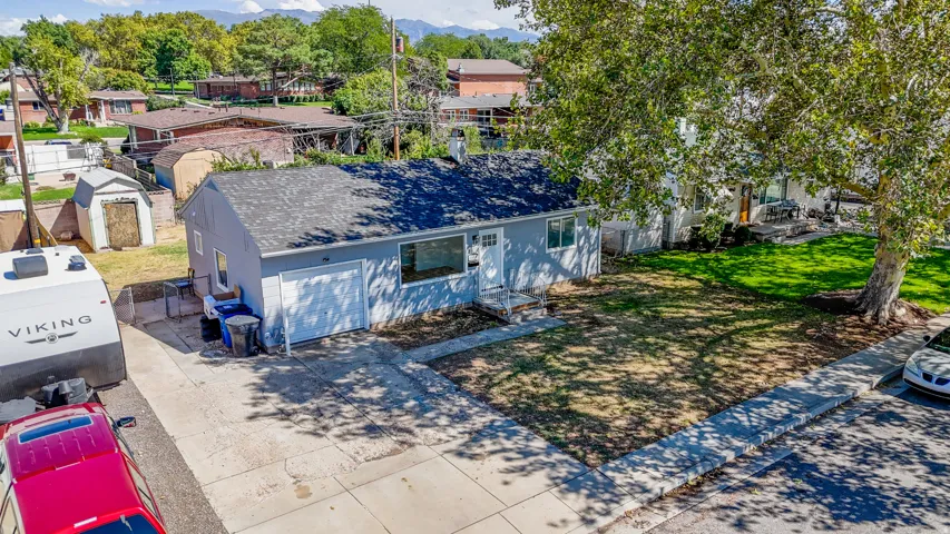 Single-story residence featuring a front lawn and a mature tree