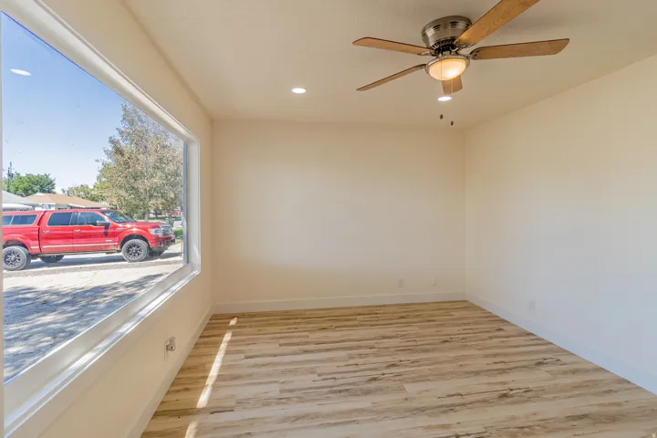 Expansive picture window, wood-finish flooring, recessed lighting, and a ceiling fan with integrated light