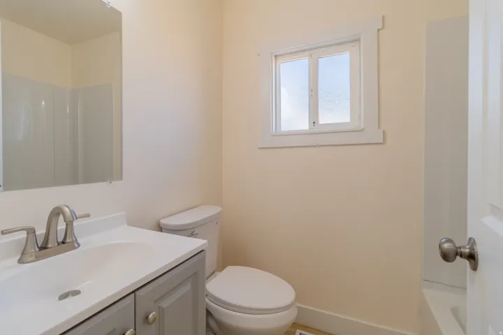 Bathroom featuring a single vanity with gray cabinetry, brushed nickel faucet, and a window with white trim