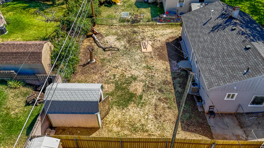 Fenced backyard featuring a gravel path and two storage sheds