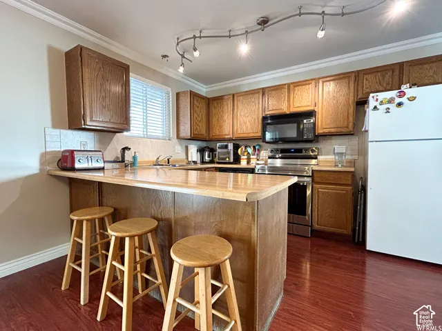 Kitchen featuring wood-finish cabinetry, stainless steel appliances, laminate countertops, and wood-finish flooring