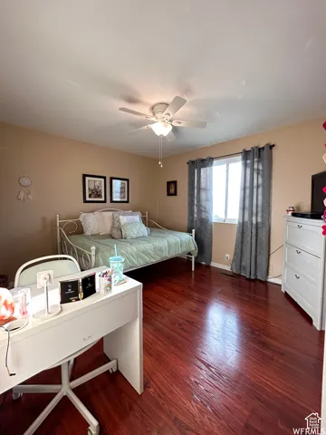 Rich wood-finish flooring, ceiling fan with integrated lighting, and neutral wall tones