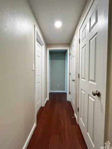 Wood-finish flooring with recessed ceiling lighting, light neutral wall paint, and white panel doors