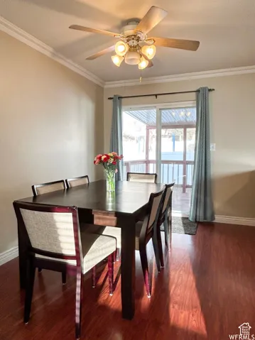 Crown molding, wood-finish flooring, ceiling fan with integrated lighting, sliding glass door, and outdoor decking