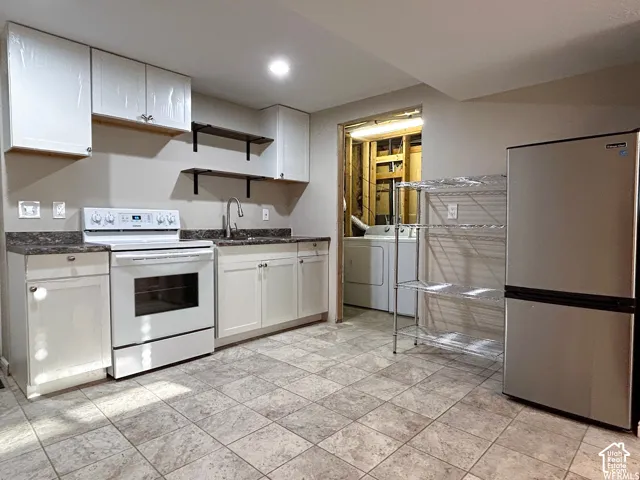 Spacious kitchen featuring white cabinetry, stainless steel appliances including a range and refrigerator, tile flooring, and ample counter space with a neutral-tone countertop