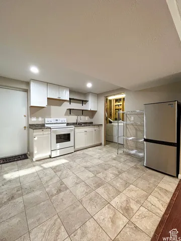 Kitchen area featuring white cabinetry, stone-finish countertops, stainless steel appliances, and tile flooring