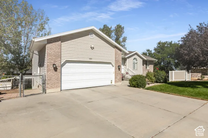Exterior featuring light-colored siding, brick accents, a two-car garage, and a concrete driveway