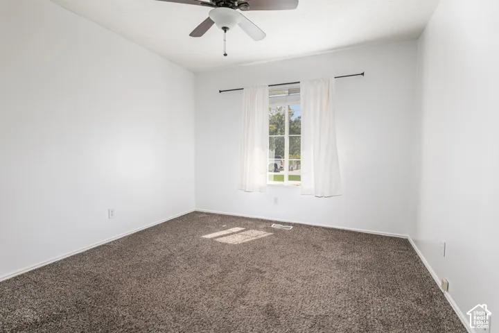 Recessed window with white curtains, ceiling fan, and grey carpet flooring