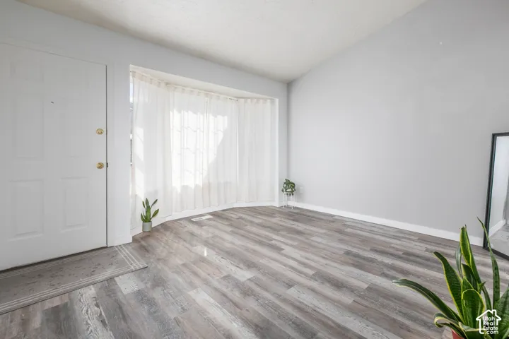 Entryway featuring a white paneled door, wood-finish flooring, and a curved window with sheer drapery