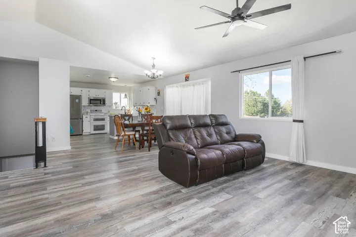 Vaulted ceilings, wood-finish flooring, stainless steel appliances, kitchen cabinetry, and a ceiling fan