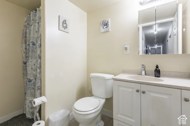 Bathroom featuring a single vanity with storage, a white toilet, and a combination shower/tub