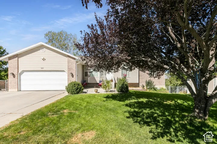 Exterior featuring brick accents, horizontal siding, attached garage, concrete driveway, and front lawn
