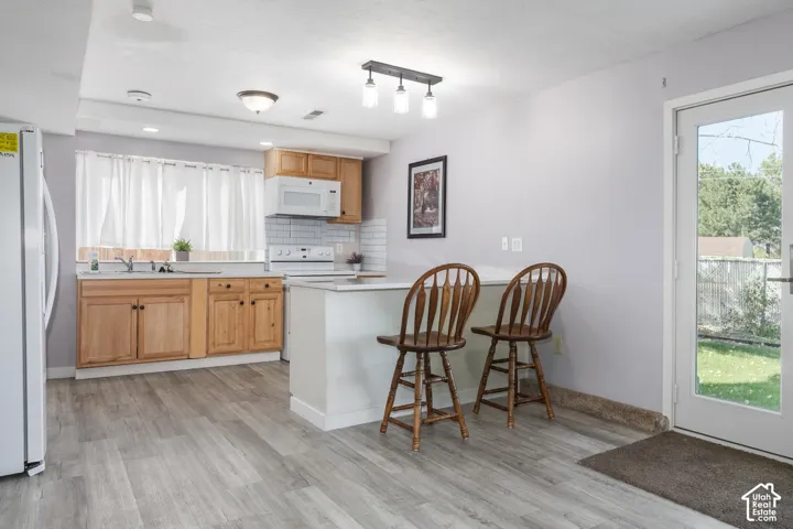 Kitchen featuring wood-finish cabinetry, white subway tile backsplash, white countertops, and stainless steel appliances