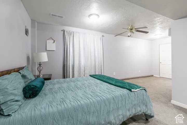 Wall-to-wall carpeting with light gray walls, featuring a ceiling-mounted fan and flush-mount lighting fixtures