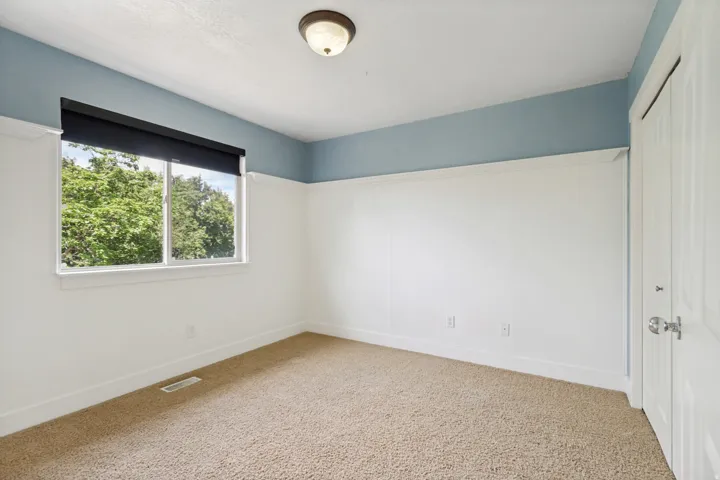Carpeted flooring, window with natural light, wall paneling, ceiling-mounted light fixture, and a solid door