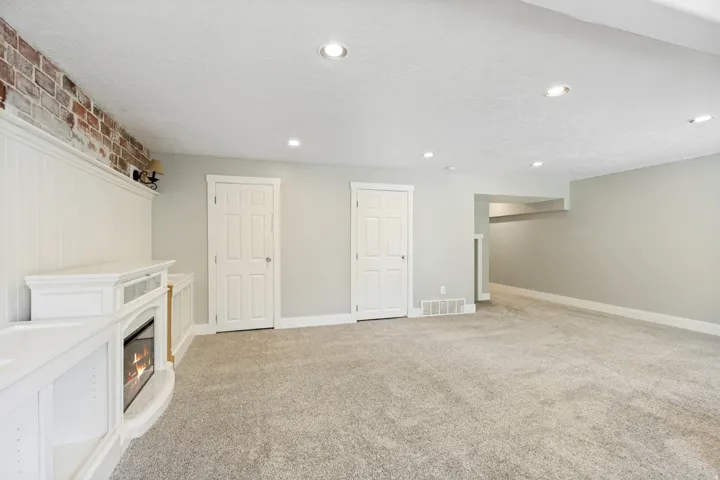 Recessed lighting, light gray wall paint, built-in media console, electric fireplace, and gray carpet