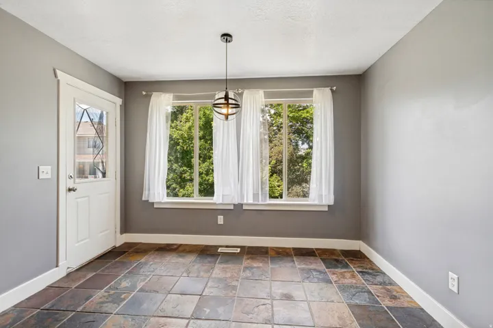 Tile flooring with varied natural tones, white trim, and a contemporary ceiling light fixture