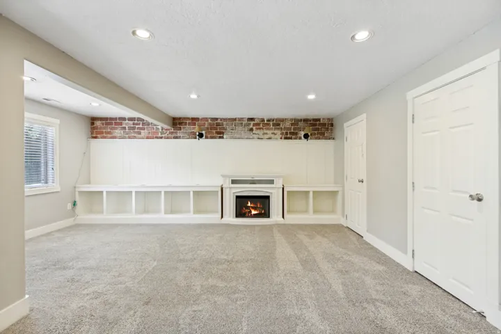 Recessed lighting illuminates the brick accent wall, built-in shelving, and white paneling