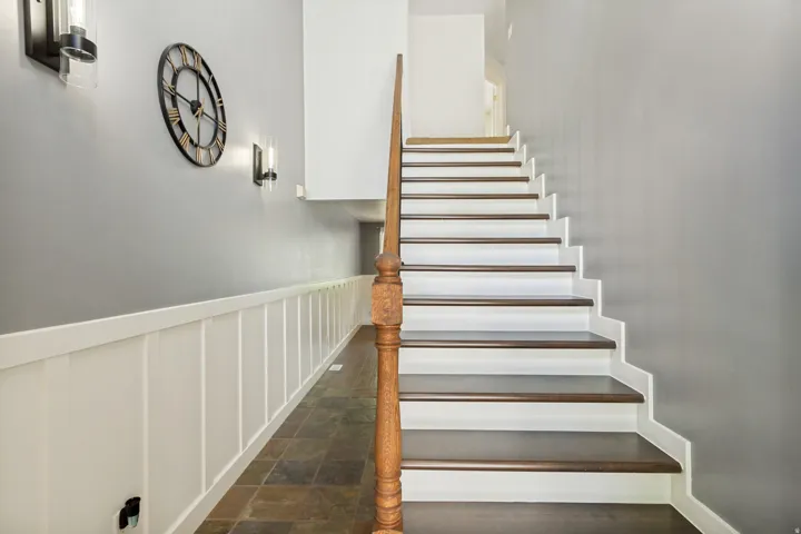 Hardwood stair treads with white risers, wood baluster, wainscoting, and tile flooring