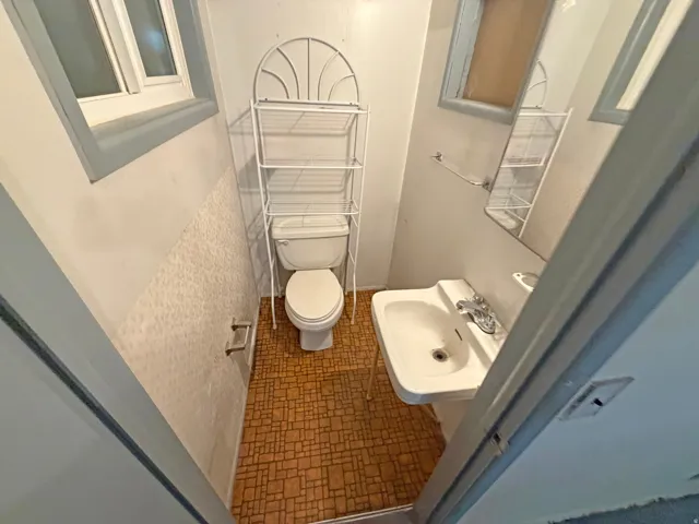 Pedestal sink with chrome faucet, toilet, and patterned floor tile