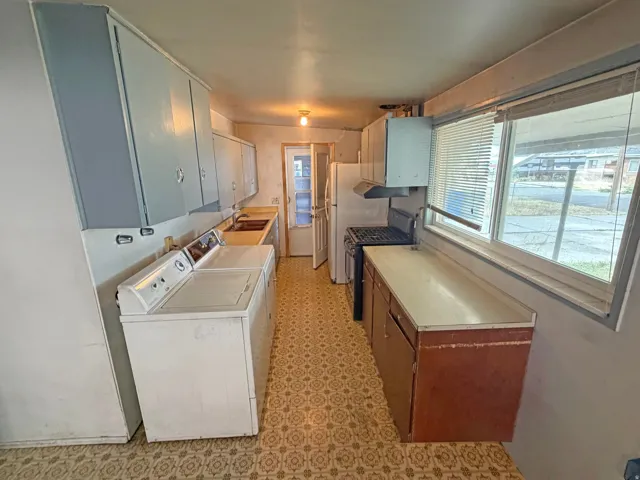 Kitchen area featuring light-toned upper cabinetry, built-in window, and patterned floor covering