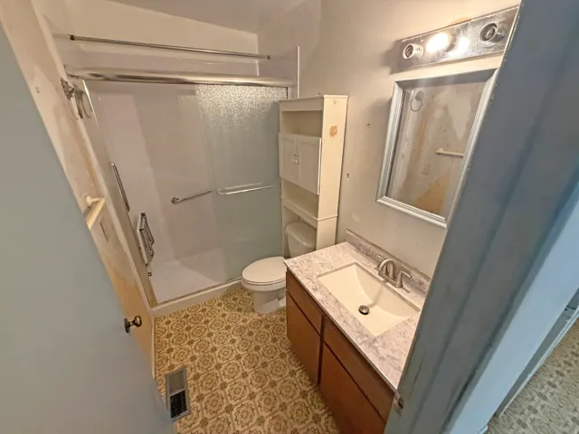 Bathroom featuring a vanity with a white rectangular sink, framed mirror, and a shower with a sliding glass door