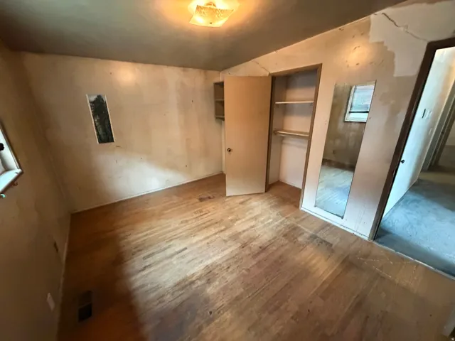 Hardwood flooring, built-in closet with shelving, ceiling-mounted light fixture, and window