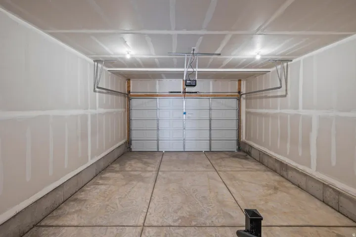Interior garage space with a concrete floor, overhead lighting, and an automatic garage door opener