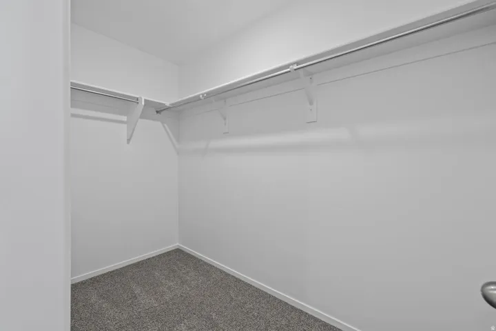 Walk-in closet with ample storage, featuring L-shaped shelving and hanging rods