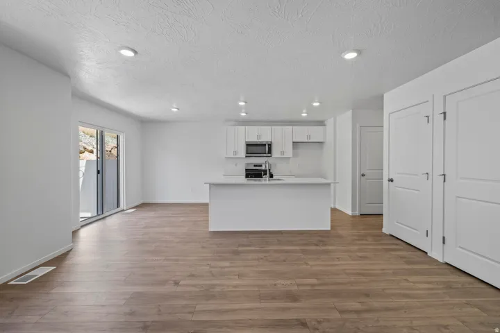 Open-concept living area featuring wood-finish flooring, recessed lighting, and a kitchen island with an undermount sink