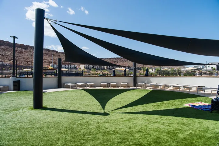 Expansive artificial turf area with overhead shade sails and surrounding lounge seating