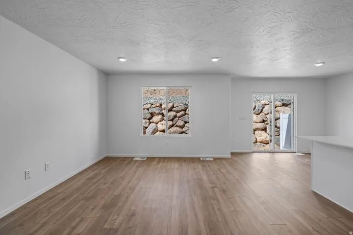 Wood-finish flooring, recessed ceiling lighting, light-toned walls, and a sliding glass door