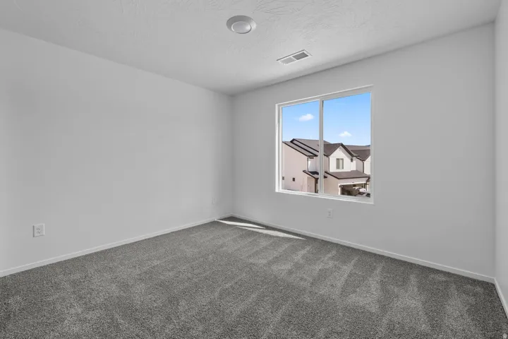 Spacious room featuring neutral carpeting, a large window, and a ceiling-mounted light fixture