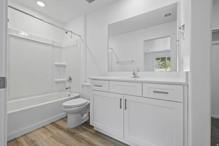 White vanity with a single basin sink, chrome faucet, and ample storage