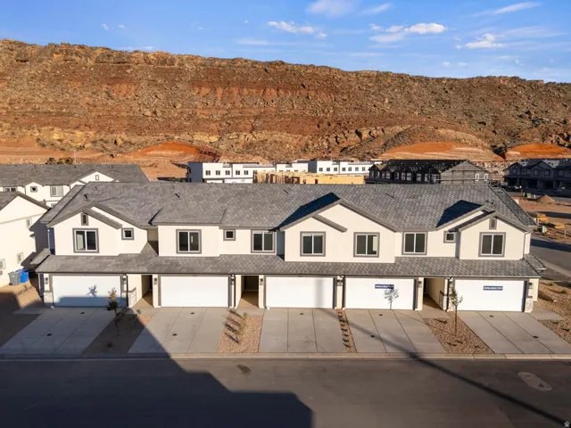 Multi-unit property featuring light-colored siding, dark gray roofing, and individual garage doors