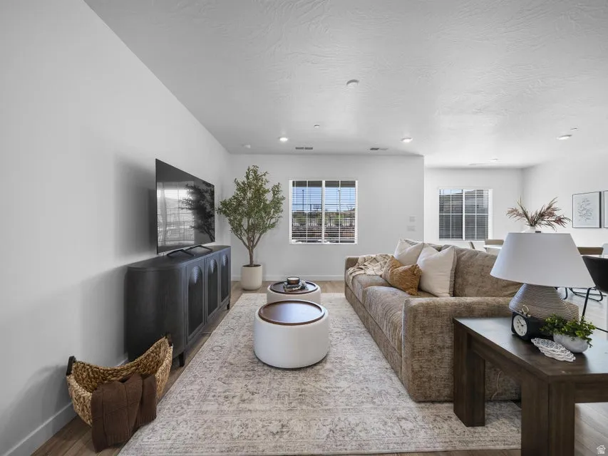 Expansive living area with wood-finish flooring, recessed lighting, and large windows
