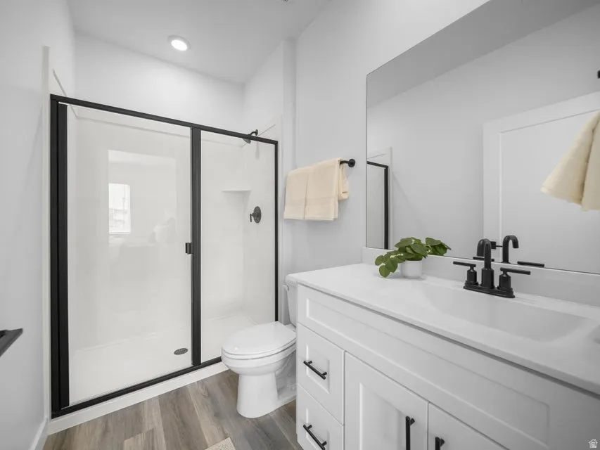 Bathroom featuring a white vanity with black hardware, a rectangular undermount sink, and a black-framed glass shower enclosure