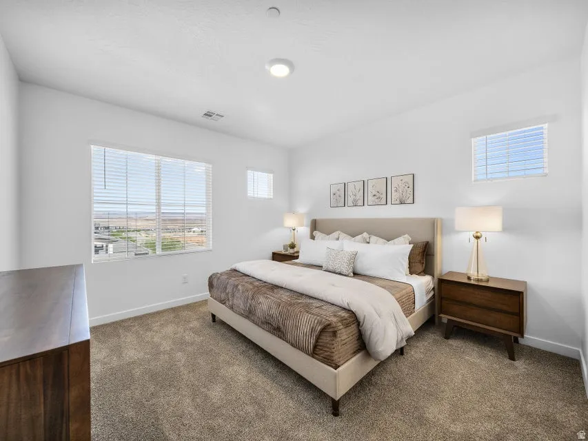 Wall-to-wall carpeting with a light-colored headboard and a window