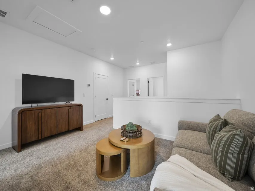 Recessed lighting, wall-to-wall carpeting, and a white wall finish