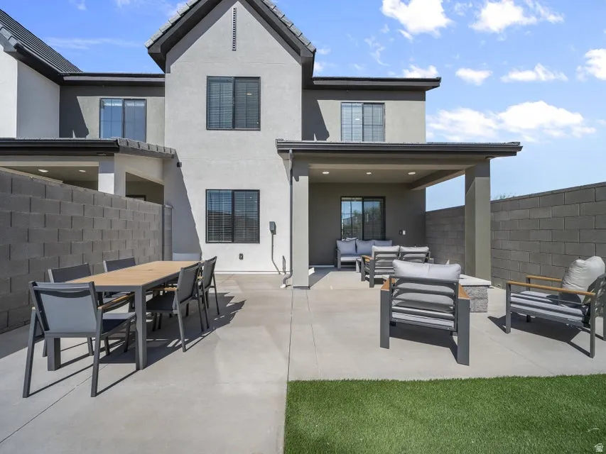 Rear exterior with a concrete patio, covered outdoor living area, and a section of artificial turf