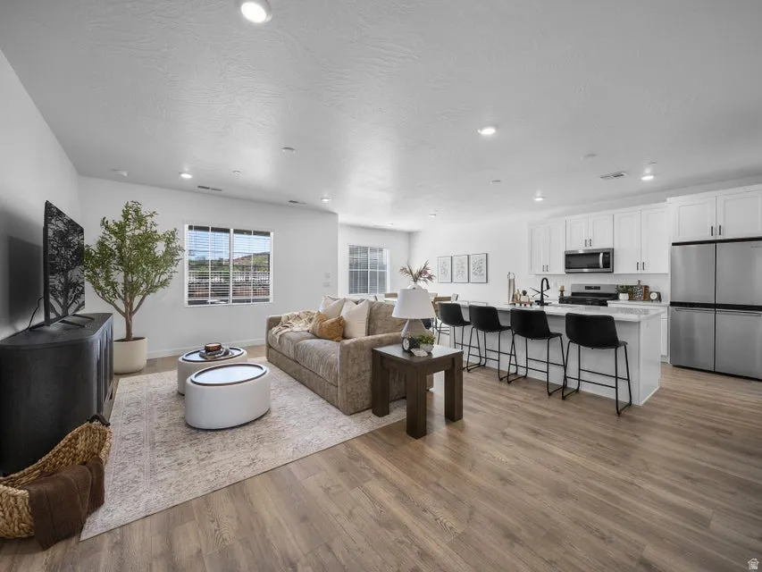 Open-concept living space featuring wood-finish flooring, recessed lighting, and a kitchen island with seating