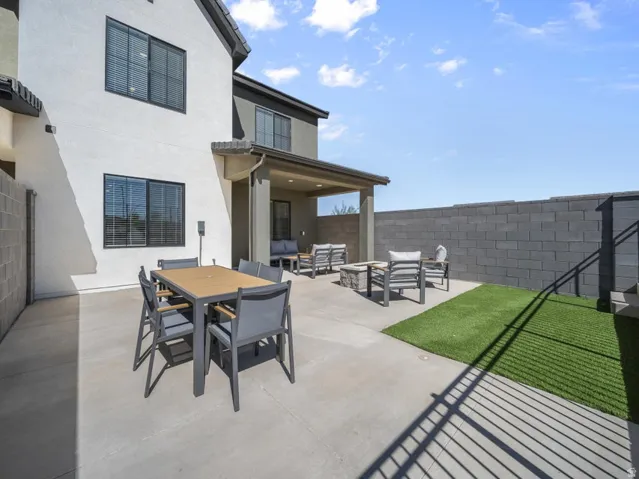 Expansive concrete patio with dedicated artificial turf area, privacy block wall, and covered patio structure