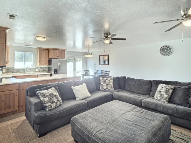 Open-concept living space with wood-finish cabinetry, light-toned countertops, and a full stainless steel appliance suite