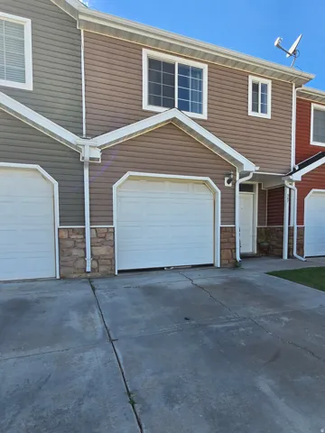 Multi-level exterior with horizontal siding, stone veneer accents, an attached garage, and a concrete driveway