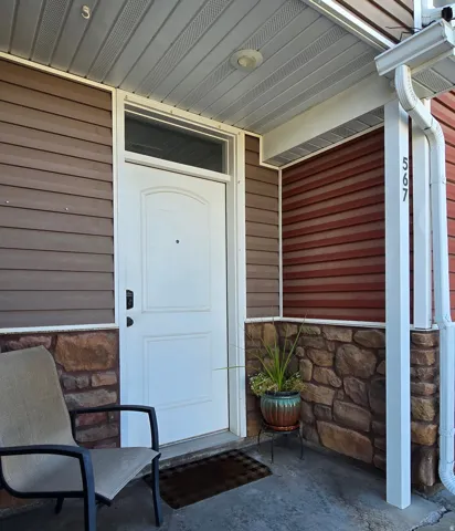 Entryway featuring horizontal siding, stone veneer accents, and a white paneled door with transom window