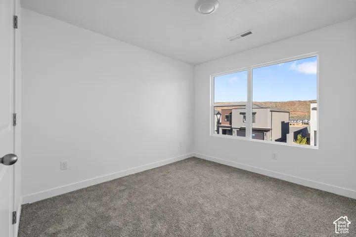 Window with surrounding landscape, neutral wall paint, gray carpeting, and white trim