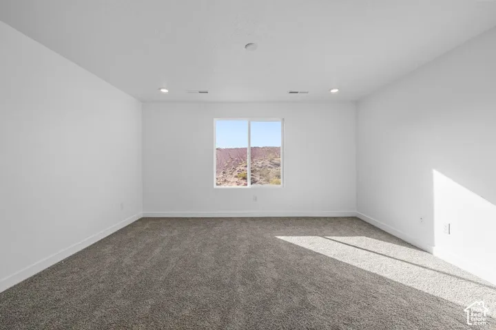Recessed ceiling lighting, white walls, gray carpet, and a window framing a desert landscape
